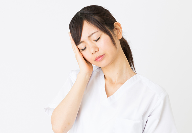 耳に手をあて、首を横に傾ける女性