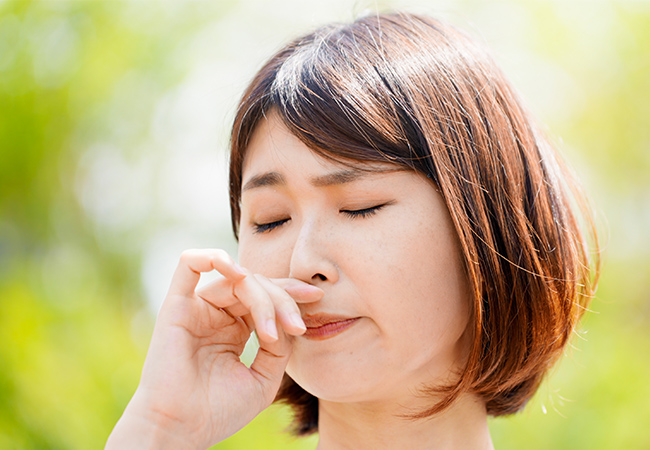 鼻を手でおさえる女性